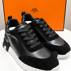 baskets noires devant une boîte orange de luxe